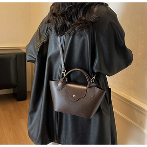 Close-up of dark brown leather handbag with lychee texture and gold metal buckle detail