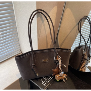 Détail d'un sac cabas en daim marron avec pendentifs étoile et petit ours mignon