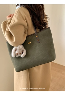Détail du sac fourre-tout en daim vert foncé avec bandoulière en cuir et breloque lapin