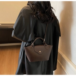 Detail shot of the dark brown lychee textured leather dumpling bag worn by a model