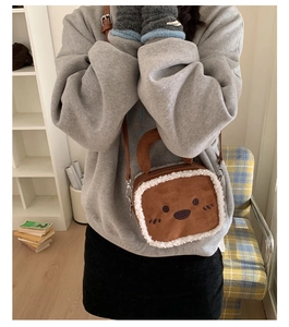 Close-up of brown plush crossbody bag with cartoon embroidery and fleece trim on a model