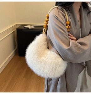 Detail of white faux fur shoulder bag with decorative wooden beads and woven handle design