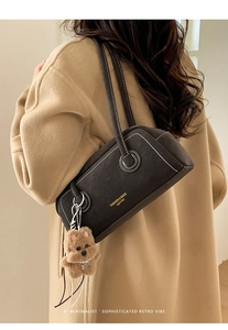 Detail of dark brown leather underarm bag with white stitching and puppy charm