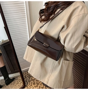 Detail of dark brown matte leather shoulder bag worn with a beige trench coat