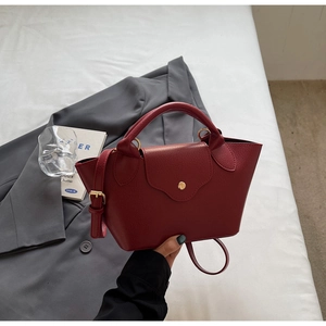 Detail of red textured leather dumpling handbag with top handle and magnetic closure
