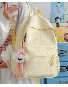 Detailed side view of yellow polka dot backpack with a cute plush puppy charm detail