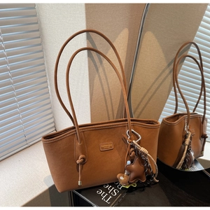 Détail du sac cabas en similicuir caramel avec pendentif étoile et bandoulière à nœuds