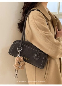 Chic dark grey underarm bag with contrast stitching and plush dog charm on khaki coat