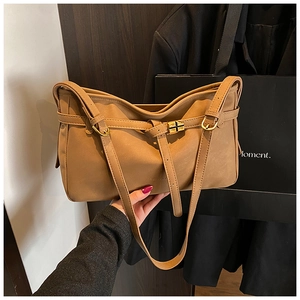 Détail du cabas en cuir mat caramel avec boucles dorées et design rétro élégant