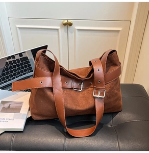 Détail du sac bandoulière en daim marron avec ceinture latérale et boucle en métal argenté