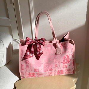 Détail du sac cabas en toile rose avec motifs de bonheur jacquard et nœud en ruban de soie