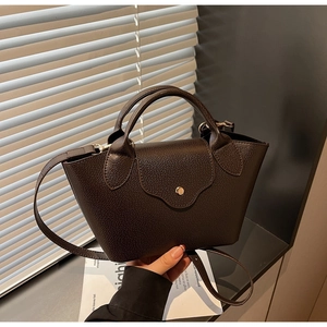 Detail of dark brown lychee leather handbag with metal snap button and top handle