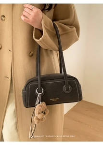 Close-up of black leather Boston bag with contrast white stitching and puppy charm