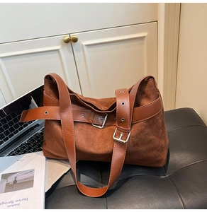 Gros plan du sac cabas en daim marron avec ceinture en cuir et boucle argentée sur banc