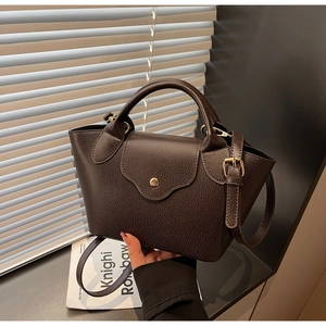 Close-up of dark brown lychee leather texture and vintage gold buckle on handbag
