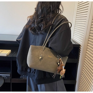 Détail du sac cabas en cuir vert olive avec une bandoulière nouée et des breloques étoiles