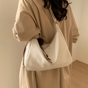 Close-up of off-white hobo bag with soft leather texture and stylish fur ball charm