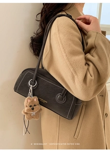Detail view of retro grey shoulder bag with contrast stitching and teddy pendant