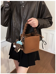 Detail of brown lychee texture bucket bag with chain strap and teddy bear charm