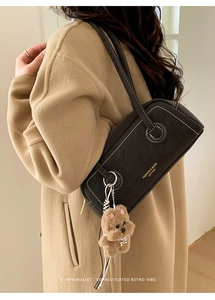 Detail of dark brown Boston shoulder bag with contrast stitching and plush dog charm