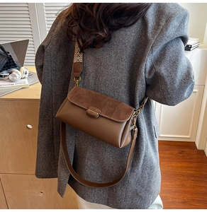 Detail of a brown leather crossbody bag featuring dual straps and a stylish wave pattern strap