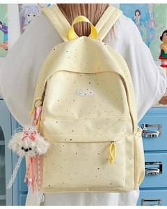 Close-up of yellow polka dot backpack with a cute plush dog charm in a campus setting