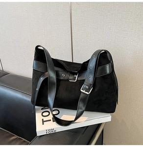Détail du sac hobo en daim noir avec boucle argentée et bandoulière à œillets métalliques