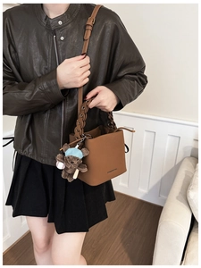 Détail du sac seau en cuir marron avec poignée tressée et breloque ours en peluche doux