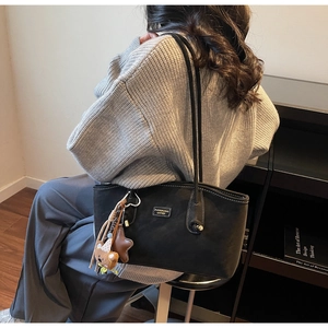 Détail du sac cabas en cuir noir avec surpiqûres blanches et pendentif ours mignon