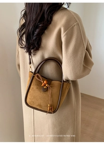 Détail du sac bandoulière en daim caramel avec perles en bois et poignées en U
