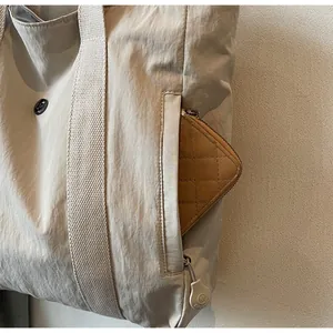 Detail showing the side zipper pocket of the canvas tote bag with a small wallet inside