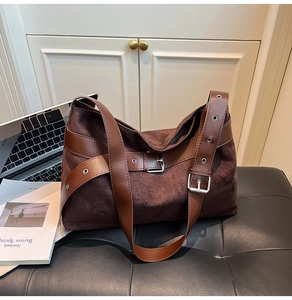 Détail du sac hobo en daim marron foncé avec boucles vintage et garnitures argentées