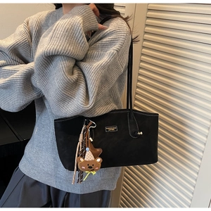 Détail du sac cabas noir avec pendentif ours et logo en cuir sur la bandoulière