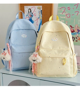 Detail of light blue and beige polka dot backpacks with cute plush puppy charms