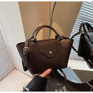 Close-up of dark brown lychee leather handbag showing handle and metal clasp detail