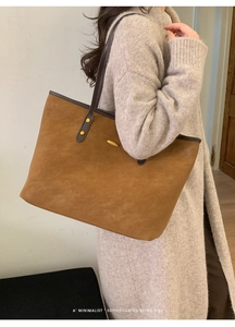 Détail d'un grand sac cabas en daim marron avec rivets dorés et poignées en cuir pour femme