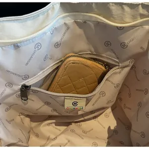 Macro shot of large tote bag interior showing zippered pocket and brand logo lining