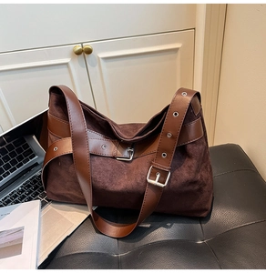 Détail du sac en cuir dépoli marron foncé avec œillets métalliques sur la bandoulière large