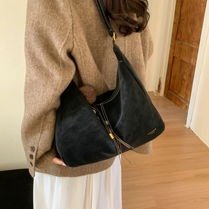 Detail of black hobo bag with white contrast stitching, gold buckle, and furry charm