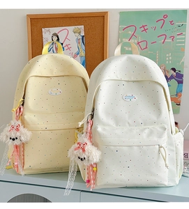 Close-up of lightweight polka dot backpacks in yellow and beige with cute plush charms