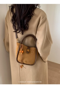 Détail du sac seau rétro en daim avec poignée ronde et élégant gland en perles de bois