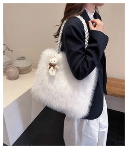 Close-up of fluffy white faux fur tote bag with braided handle and cute bear charm