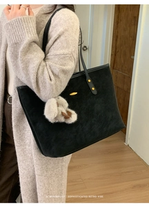 Détail du cabas en daim noir avec rivets dorés et un charmant lapin en peluche gris