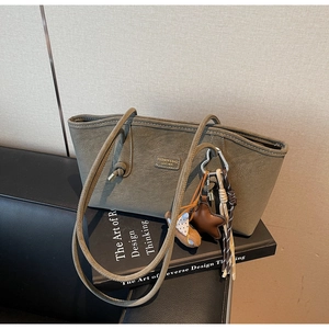 Détail du sac cabas vert foncé avec lettrage métallique et breloque en forme d'étoile