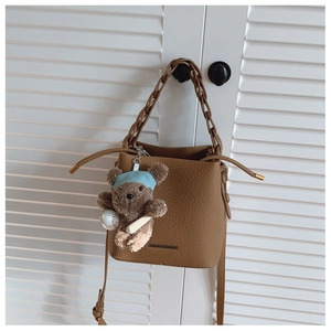 Detail of brown litchi pattern bucket bag with woven handle and bear charm