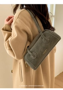 Detail view of the stitching and gold branding on the grey leather underarm shoulder bag