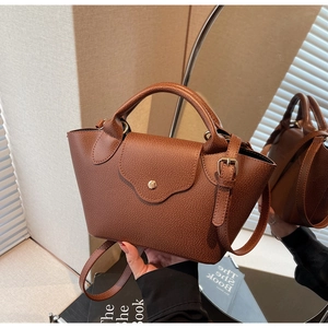 Detail of caramel brown lychee grain leather handbag with gold metal clasp and dual handles