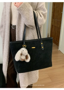 Détail du grand sac cabas noir minimaliste avec boucle dorée et breloque lapin en peluche