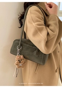 Detail of dark green suede hobo bag with contrast stitching and plush dog charm