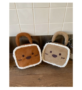 Detailed close-up of brown and beige plush square handbags with white faux fur trim on wood